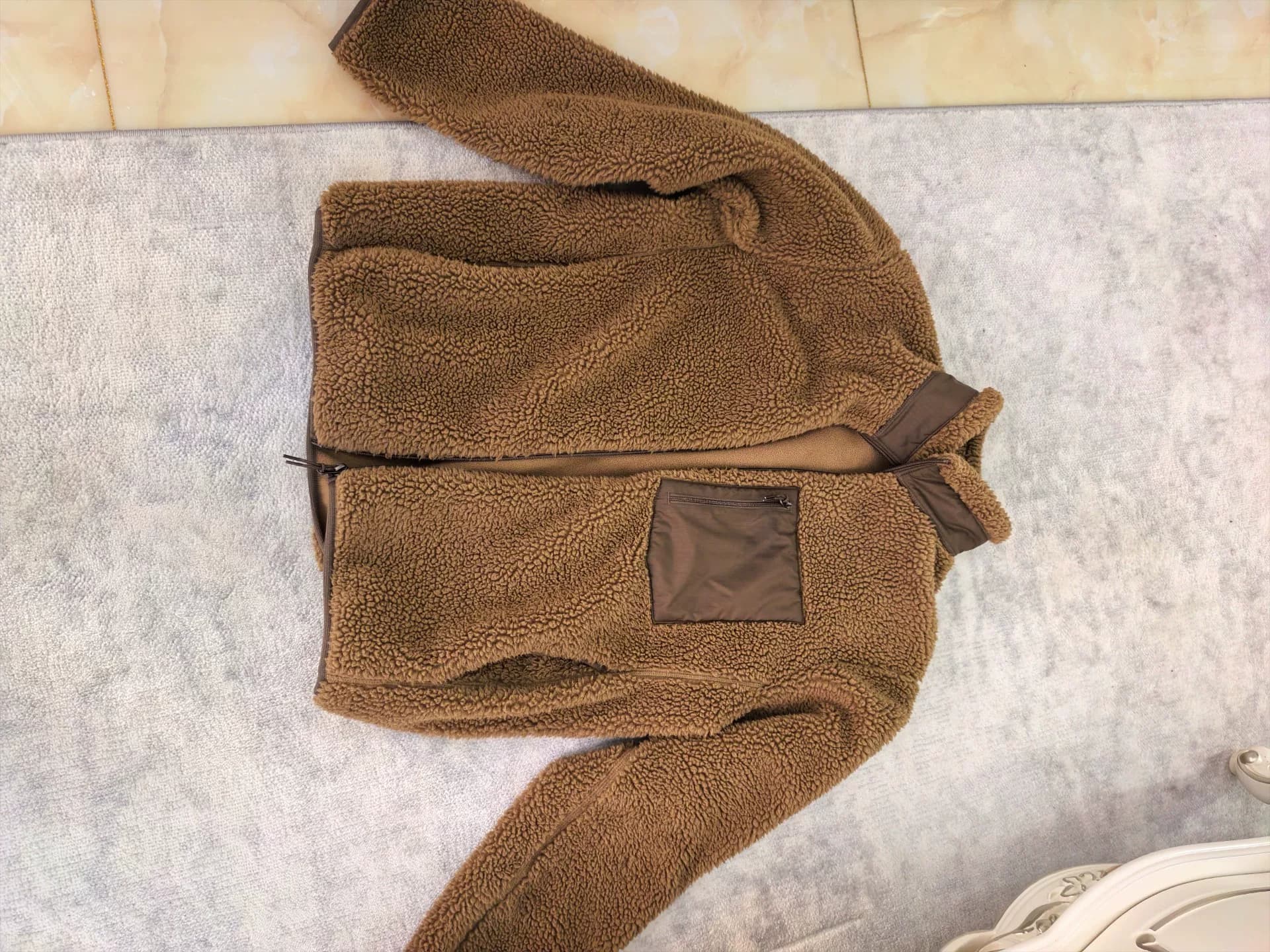 Окурки сигарет на левой манжете хлопчатобумажной куртки Uniqlo Teddy подгорели, что не влияет на износ.